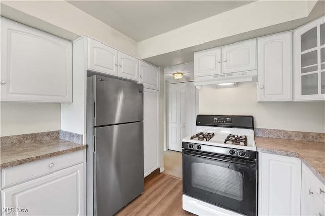 1145 Canyon View Rd Unit 206, Sagamore Hills, OH 44067 - kitchen with freestanding refrigerator, gas stove, under cabinet range hood, glass insert cabinets, and white cabinetry