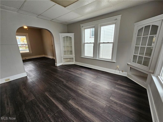 3891 W 21st St, Cleveland, OH 44109 - unfurnished room featuring arched walkways, a paneled ceiling, dark wood-style floors, and baseboards