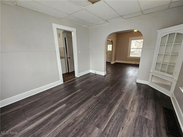 3891 W 21st St, Cleveland, OH 44109 - empty room featuring a paneled ceiling, arched walkways, dark wood finished floors, baseboards, and a wainscoted wall