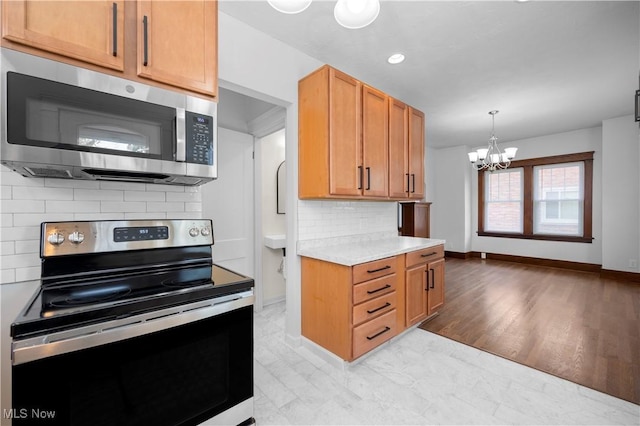 1138 W 6th St, Lorain, OH 44052 - kitchen with stainless steel appliances, a chandelier, light countertops, tasteful backsplash, and baseboards