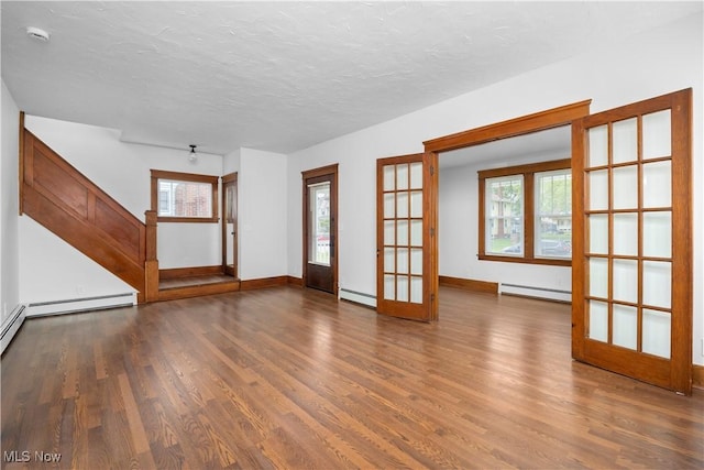 1138 W 6th St, Lorain, OH 44052 - unfurnished living room featuring baseboard heating, french doors, wood finished floors, plenty of natural light, and a textured ceiling