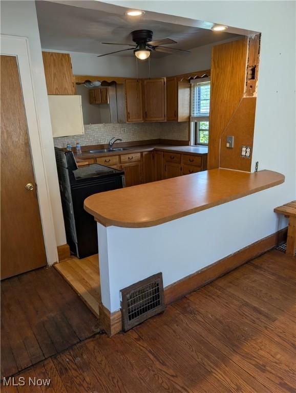 630 N Lincoln Ct, Louisville, OH 44641 - kitchen featuring black range with electric stovetop, wood finished floors, a ceiling fan, brown cabinets, and a peninsula