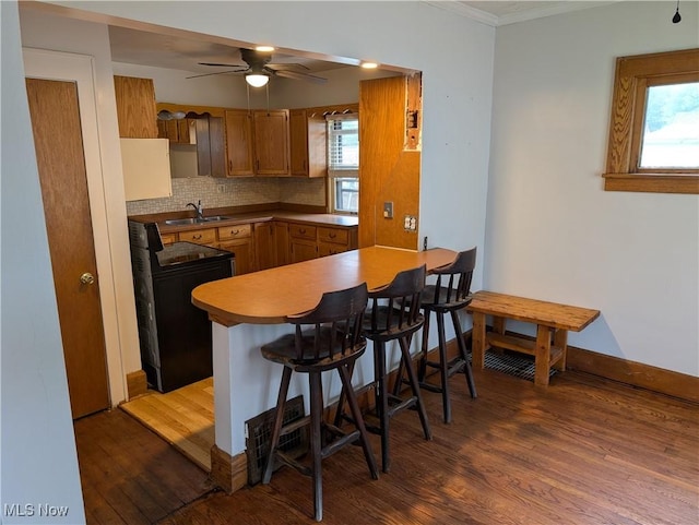 630 N Lincoln Ct, Louisville, OH 44641 - kitchen with black / electric stove, wood finished floors, a peninsula, brown cabinetry, and a ceiling fan