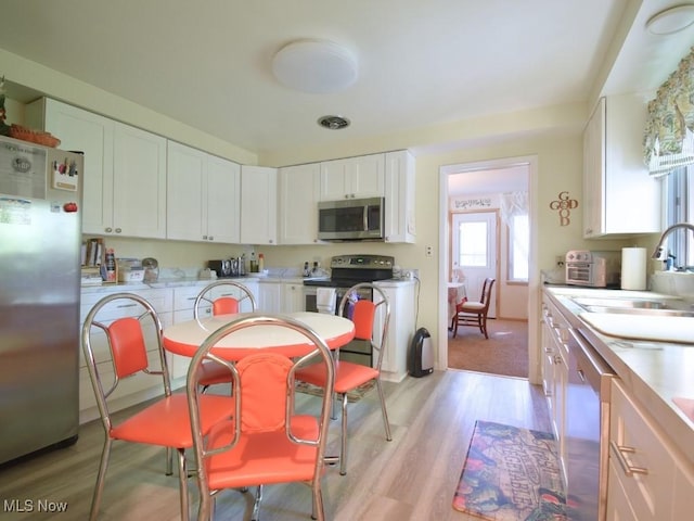 4628 Monticello Blvd, South Euclid, OH 44143 - kitchen with appliances with stainless steel finishes, white cabinetry, light wood-style floors, a sink, and light countertops