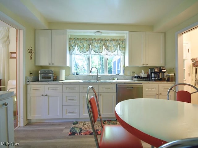 4628 Monticello Blvd, South Euclid, OH 44143 - kitchen featuring a sink, white cabinets, light wood finished floors, stainless steel dishwasher, and light countertops