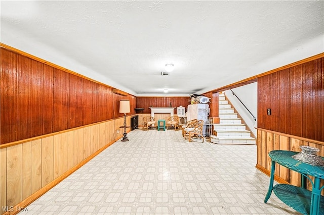 131 E 206th St, Euclid, OH 44123 - living area featuring wood walls, stairs, a textured ceiling, and wainscoting