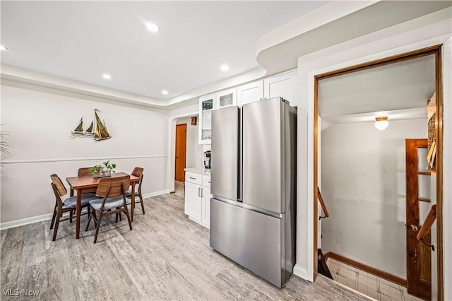 131 E 206th St, Euclid, OH 44123 - kitchen with freestanding refrigerator, white cabinetry, light wood-style floors, glass insert cabinets, and baseboards