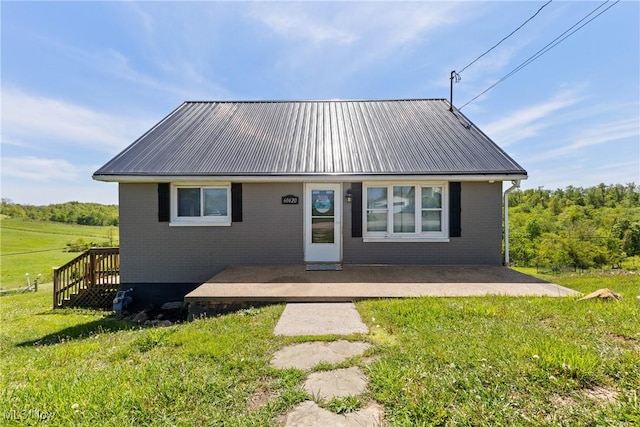 60620 Main St, Jacobsburg, OH 43933 - view of front facade featuring a front yard, brick siding, metal roof, and a patio area