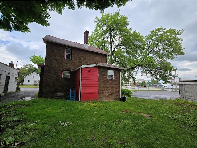 958 E Wilbeth Rd, Akron, OH 44306 - back of house featuring brick siding, a chimney, and a lawn