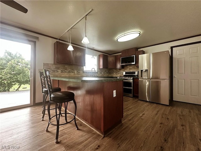 95 Cheyenne Dr, Girard, OH 44420 - kitchen with appliances with stainless steel finishes, tasteful backsplash, dark wood-style flooring, a kitchen bar, and ornamental molding
