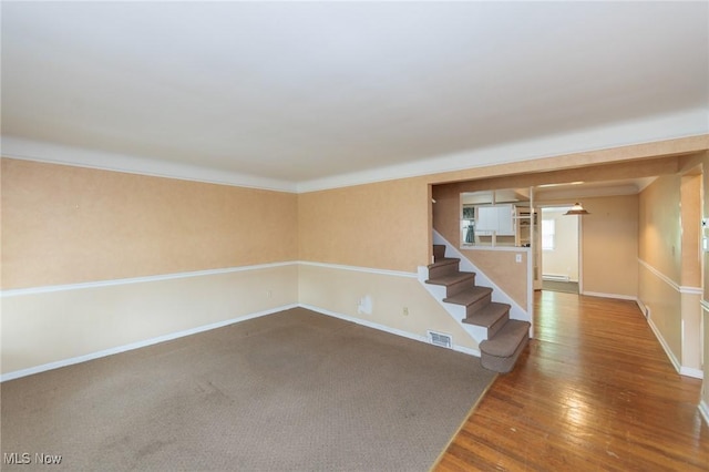 14245 Cedar Rd, South Euclid, OH 44121 - empty room featuring baseboards, wood finished floors, stairway, and a baseboard radiator