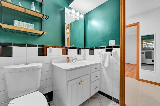 14369 E Bagley Rd, Middleburg Heights, OH 44130 - bathroom with tile walls, vanity, toilet, and wainscoting