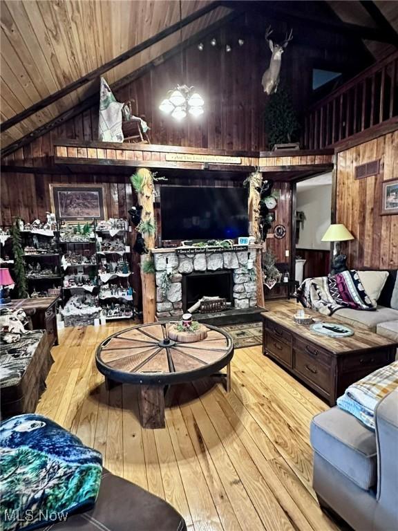 10664 W Little Kanawha Hwy, Mount Zion, WV 26151 - living area with wood walls, vaulted ceiling, wooden ceiling, a stone fireplace, and hardwood / wood-style floors