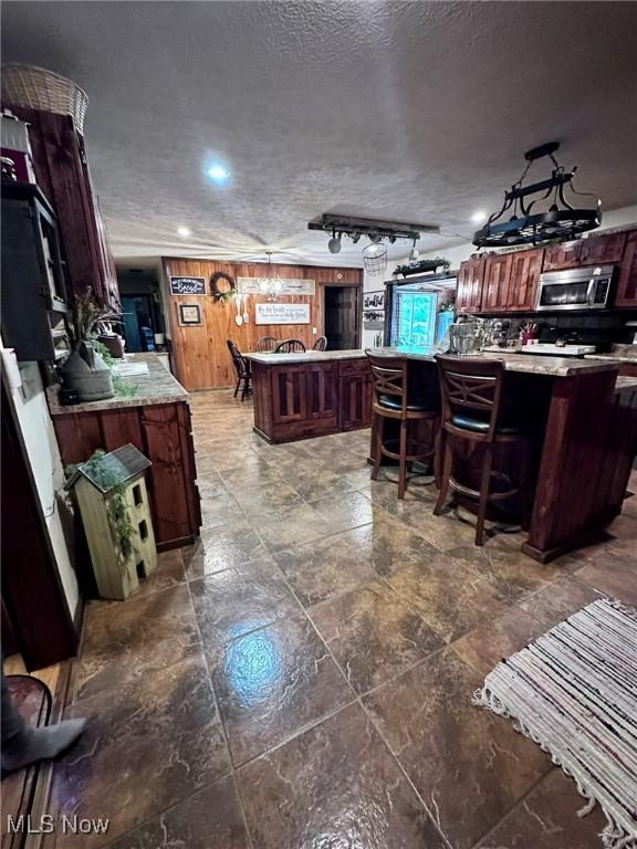 10664 W Little Kanawha Hwy, Mount Zion, WV 26151 - kitchen featuring stainless steel microwave, a kitchen island, light countertops, a kitchen bar, and a textured ceiling