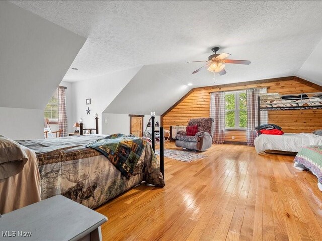 10664 W Little Kanawha Hwy, Mount Zion, WV 26151 - bedroom with wood walls, vaulted ceiling, hardwood / wood-style floors, a textured ceiling, and a ceiling fan