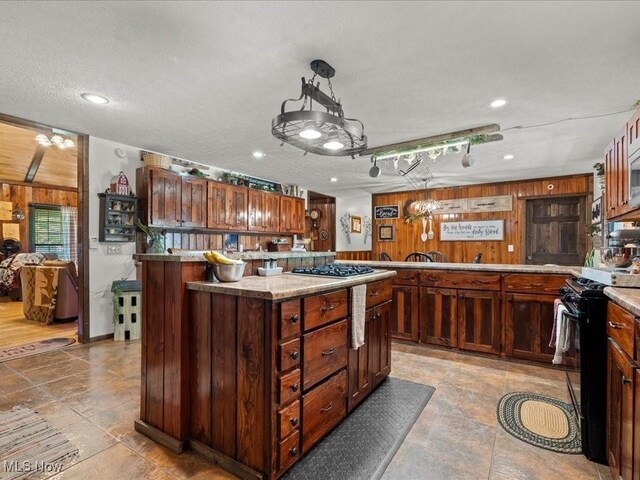 10664 W Little Kanawha Hwy, Mount Zion, WV 26151 - kitchen featuring black stove, wooden walls, stainless steel gas stovetop, recessed lighting, and a kitchen island