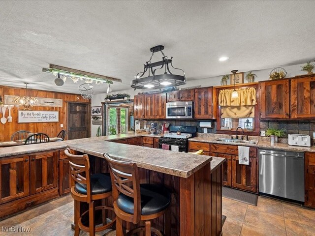 10664 W Little Kanawha Hwy, Mount Zion, WV 26151 - kitchen with appliances with stainless steel finishes, a sink, decorative backsplash, a breakfast bar, and a textured ceiling