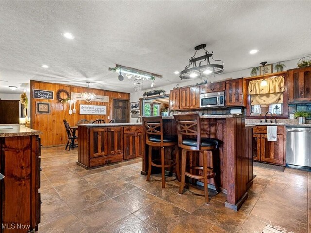 10664 W Little Kanawha Hwy, Mount Zion, WV 26151 - kitchen featuring appliances with stainless steel finishes, a kitchen island, recessed lighting, wood walls, and a kitchen bar