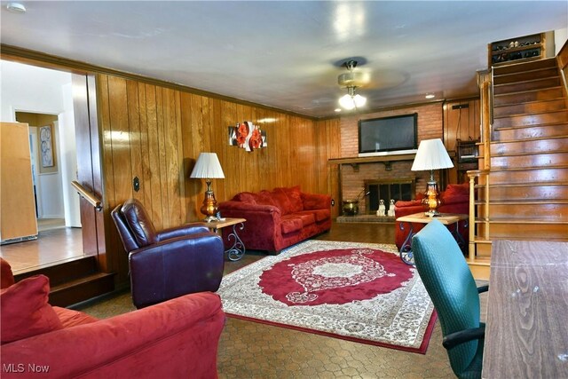 2816 E Market St, Warren, OH 44483 - living room featuring ceiling fan, a brick fireplace, stairway, and wooden walls