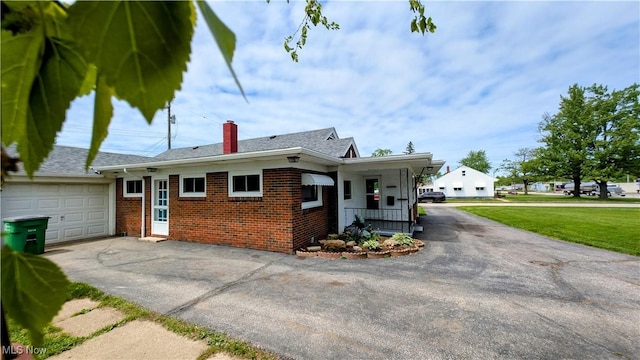 3205 State Rd, Ashtabula, OH 44004 - view of front facade with brick siding, asphalt driveway, a garage, and a chimney