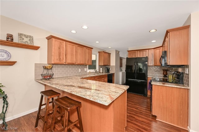 947 Trimble Pl, Sagamore Hills, OH 44067 - kitchen with black appliances, a peninsula, a sink, dark wood finished floors, and backsplash