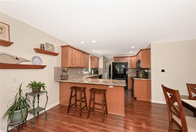 947 Trimble Pl, Sagamore Hills, OH 44067 - kitchen featuring black appliances, a peninsula, decorative backsplash, dark wood finished floors, and a breakfast bar