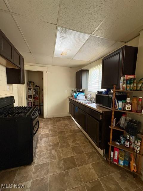 639 Bellevue Ave, Akron, OH 44307 - kitchen with black gas stove, dark brown cabinetry, a sink, and a paneled ceiling