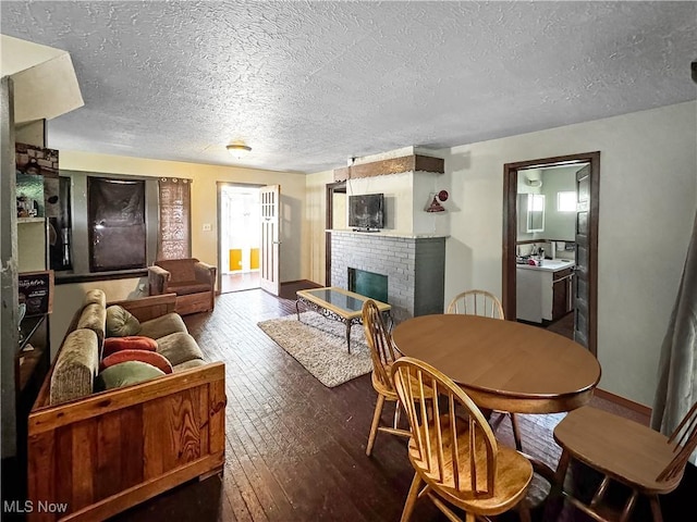 14014 Sylvia Ave, Cleveland, OH 44110 - living area featuring wood-type flooring, a textured ceiling, a fireplace, and baseboards
