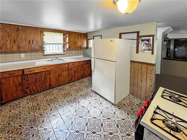 14014 Sylvia Ave, Cleveland, OH 44110 - kitchen featuring white appliances, a sink, brown cabinetry, light countertops, and decorative backsplash