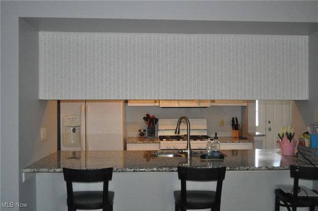 1883 Ridge Meadow Ct, Twinsburg, OH 44087 - kitchen with a sink, dark stone counters, a peninsula, and a kitchen bar