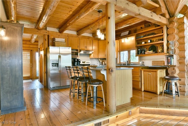 18102 Owen Rd, Middlefield, OH 44062 - kitchen with stainless steel appliances, under cabinet range hood, light wood-type flooring, rustic walls, and wooden ceiling with exposed beams