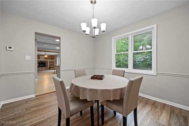 1704 Emerald Dr, Lorain, OH 44053 - dining room with a chandelier, wood finished floors, baseboards, and a fireplace with raised hearth