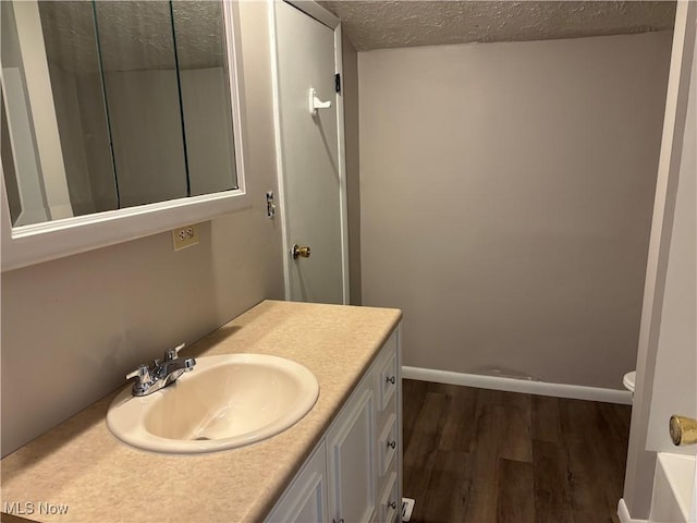 1278 Euclid Ave, Zanesville, OH 43701 - bathroom featuring wood finished floors, toilet, vanity, a textured ceiling, and baseboards