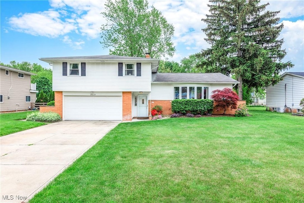 28023 Terrace Dr, North Olmsted, OH 44070 - tri-level home with brick siding, an attached garage, concrete driveway, and a front lawn