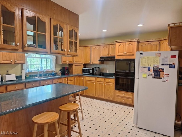 16604 Old State Rd, Middlefield, OH 44062 - kitchen with freestanding refrigerator, stainless steel microwave, a sink, under cabinet range hood, and a breakfast bar area