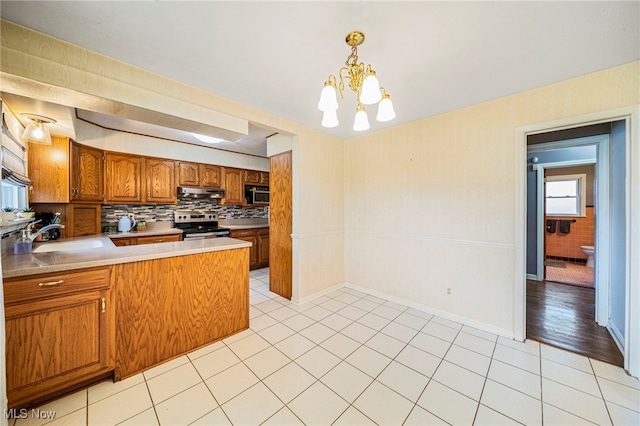 2039 S Green Rd, South Euclid, OH 44121 - kitchen with appliances with stainless steel finishes, brown cabinets, decorative backsplash, a peninsula, and light countertops