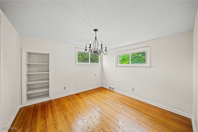 2039 S Green Rd, South Euclid, OH 44121 - spare room with a chandelier, baseboards, built in features, and light wood-type flooring
