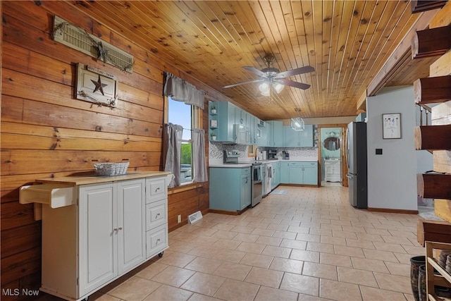 9434 Trinity Church Rd, Lisbon, OH 44432 - kitchen with appliances with stainless steel finishes, light countertops, blue cabinets, a ceiling fan, and wood walls