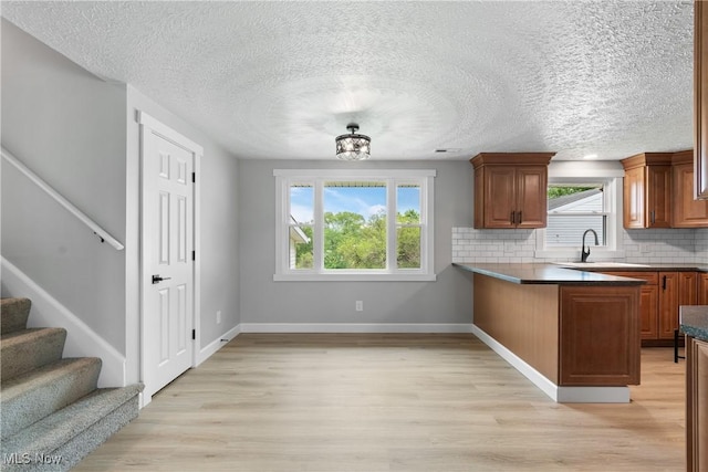 4426 Dueber Ave SW, Canton, OH 44706 - kitchen featuring brown cabinets, tasteful backsplash, light wood-type flooring, and a textured ceiling