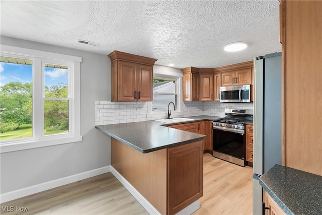 4426 Dueber Ave SW, Canton, OH 44706 - kitchen with appliances with stainless steel finishes, a sink, a peninsula, light wood-style flooring, and a textured ceiling