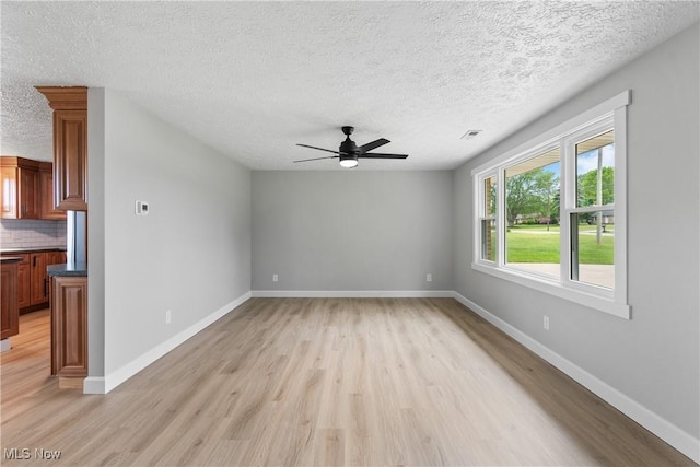 4426 Dueber Ave SW, Canton, OH 44706 - spare room featuring light wood-type flooring, ceiling fan, a textured ceiling, and baseboards