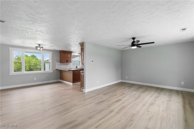 4426 Dueber Ave SW, Canton, OH 44706 - unfurnished living room featuring light wood-style floors, a textured ceiling, ceiling fan, a sink, and baseboards