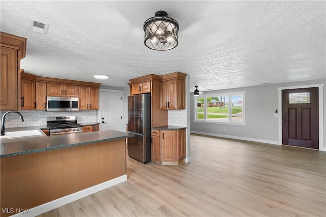 4426 Dueber Ave SW, Canton, OH 44706 - kitchen featuring appliances with stainless steel finishes, a sink, light wood-type flooring, dark countertops, and backsplash