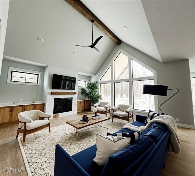 275 Glengarry Dr, Aurora, OH 44202 - living room with light wood-type flooring, beamed ceiling, a glass covered fireplace, a ceiling fan, and high vaulted ceiling