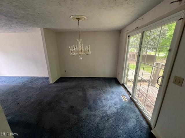 201 Morgan Dr, Painesville, OH 44077 - unfurnished dining area featuring dark colored carpet, a chandelier, and a textured ceiling