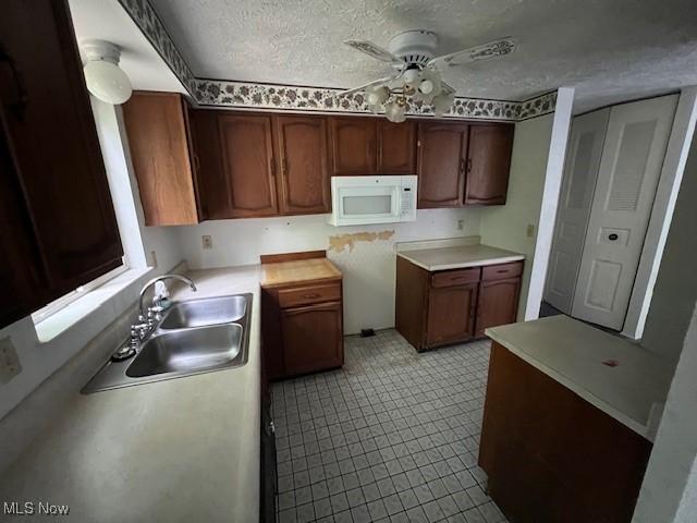 201 Morgan Dr, Painesville, OH 44077 - kitchen featuring white microwave, ceiling fan, a sink, a textured ceiling, and light countertops