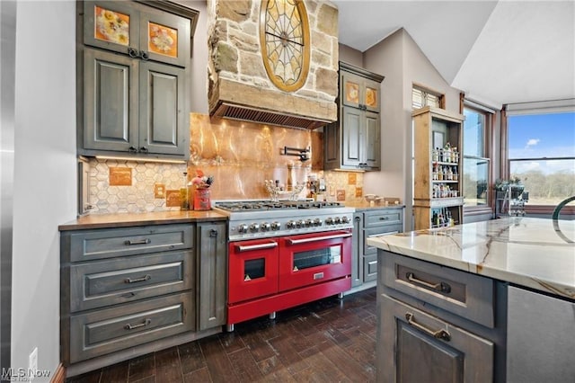10366 Immel St NE, Canton, OH 44721 - kitchen with range with two ovens, custom range hood, decorative backsplash, dark wood finished floors, and glass insert cabinets
