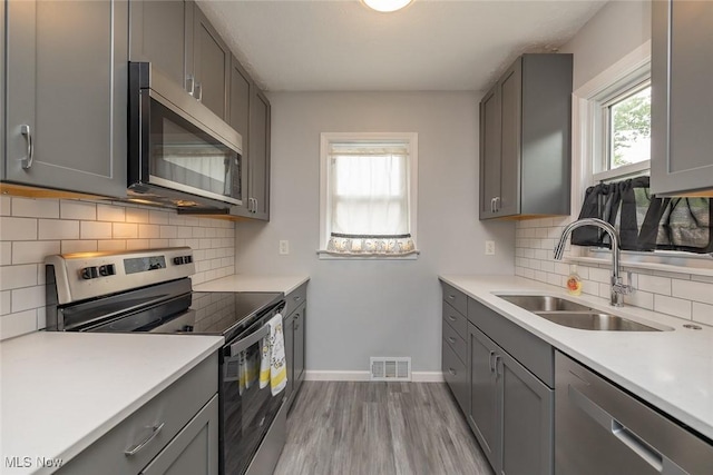 5963 Porter Rd, North Olmsted, OH 44070 - kitchen with stainless steel appliances, a sink, gray cabinets, and light wood-style flooring