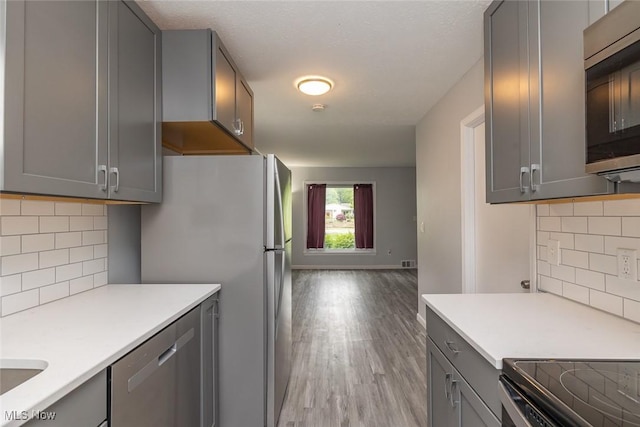 5963 Porter Rd, North Olmsted, OH 44070 - kitchen with appliances with stainless steel finishes, gray cabinetry, light wood finished floors, and light countertops