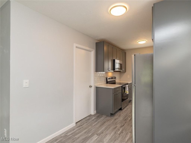 5963 Porter Rd, North Olmsted, OH 44070 - kitchen with appliances with stainless steel finishes, gray cabinets, tasteful backsplash, light wood finished floors, and light countertops